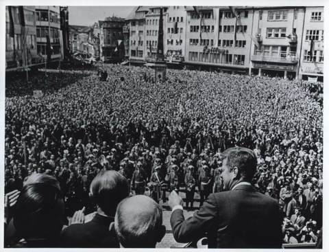 President-Kennedy-Waves-A-Greeting-as-He-Begins-His-Speech-in-Bonn-to-a-Crowd-Which-Flows-into-Buildings-on-the-City-Hall-Square-and-on-into-Adjacent-Side-Streets